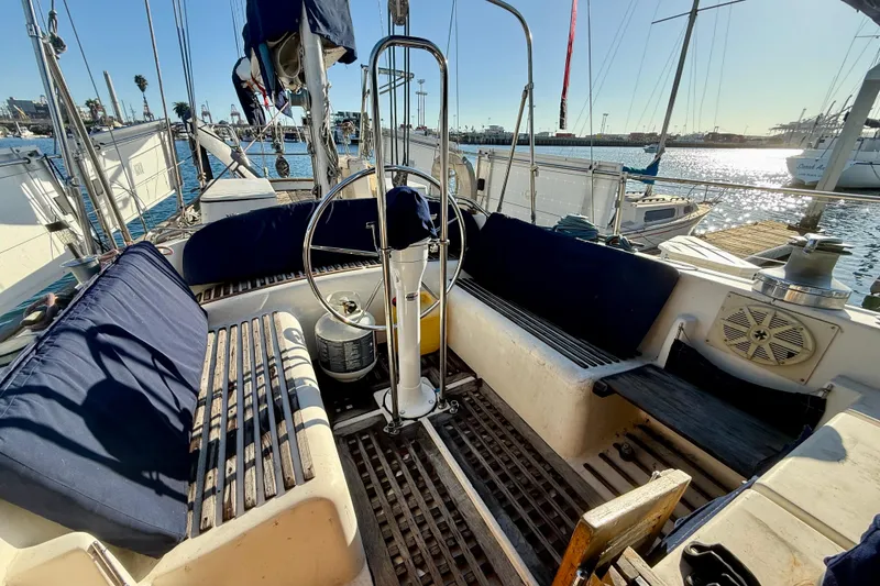 Cockpit of 1981 Mariner Mayflower sailboat with wooden seating and steering wheel, docked at marina.