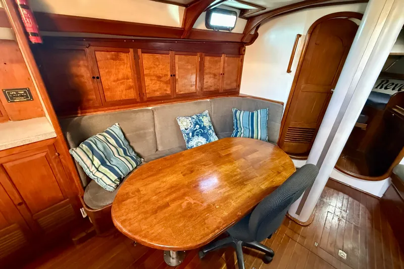 Cozy 1981 Mariner Mayflower yacht interior with wooden table, cushioned seating, and striped pillows.