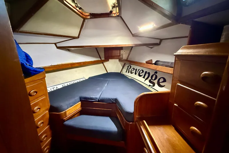 1981 Mariner Mayflower cabin interior with wooden drawers and blue cushions.