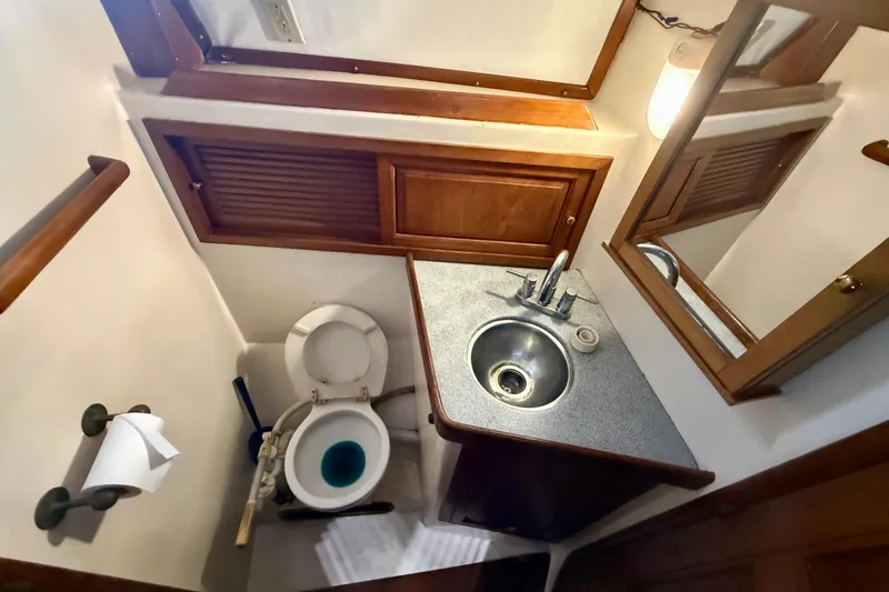 Compact 1981 Mariner Mayflower boat bathroom with sink, toilet, and wooden cabinetry.
