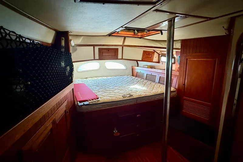 Cozy cabin interior of 1981 Mariner Mayflower yacht with wooden furnishings and a bed.