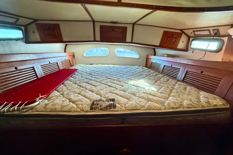 Interior cabin of 1981 Mariner Mayflower boat with bed and wooden storage.