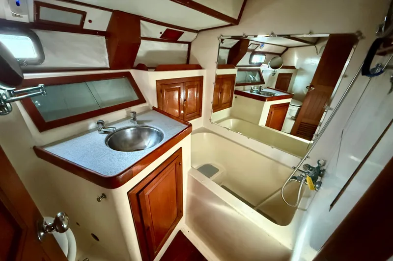 1981 Mariner Mayflower yacht bathroom with sink, mirror, and wooden cabinetry.