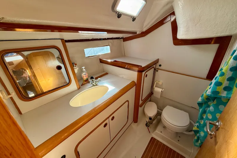 Beneteau Oceanis 390 yacht bathroom, 1988 model, featuring sink, mirror, and toilet.