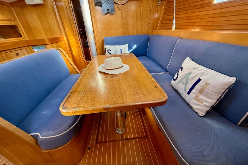 Interior of 1988 Beneteau Oceanis 390 sailboat with blue seating and wooden table.