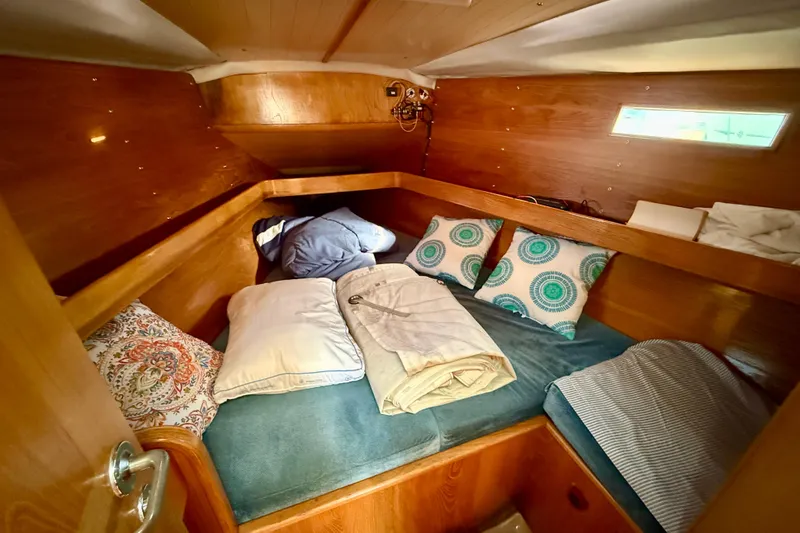 Cozy cabin interior of 1988 Beneteau Oceanis 390 sailboat with pillows and bedding.