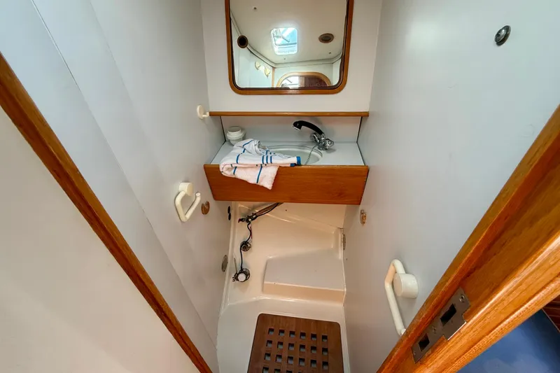 Compact bathroom in 1988 Beneteau Oceanis 390 sailboat with wooden accents and mirror.
