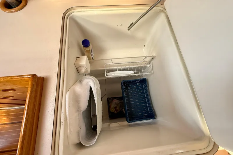 Interior view of a Beneteau Oceanis 390 refrigerator, showcasing storage compartments.