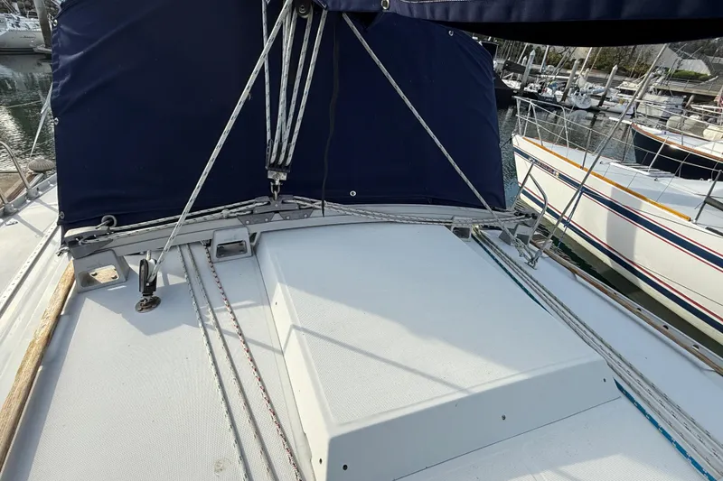 1988 Beneteau Oceanis 390 sailboat deck with blue canvas cover in marina.