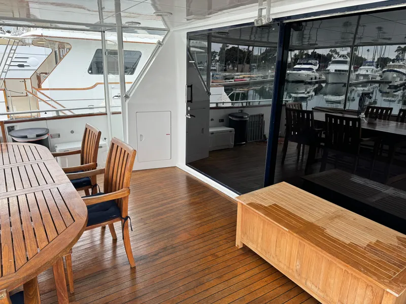 Outdoor deck of 1990 Versilcraft Challenger Motor Yacht with wooden furniture and marina view.