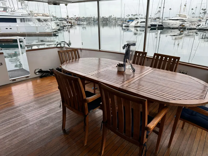 1990 Versilcraft Challenger Motor Yacht with wooden deck and dining area in marina setting.