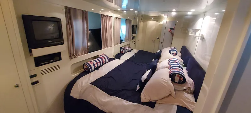 Luxurious bedroom interior of 1990 Versilcraft Challenger Motor Yacht with cozy bedding and TV.