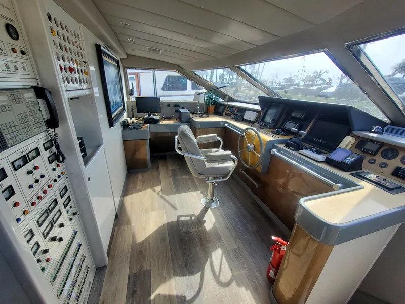 Versilcraft Challenger Motor Yacht 1990 helm with control panels and captain's chair, featuring panoramic windows.