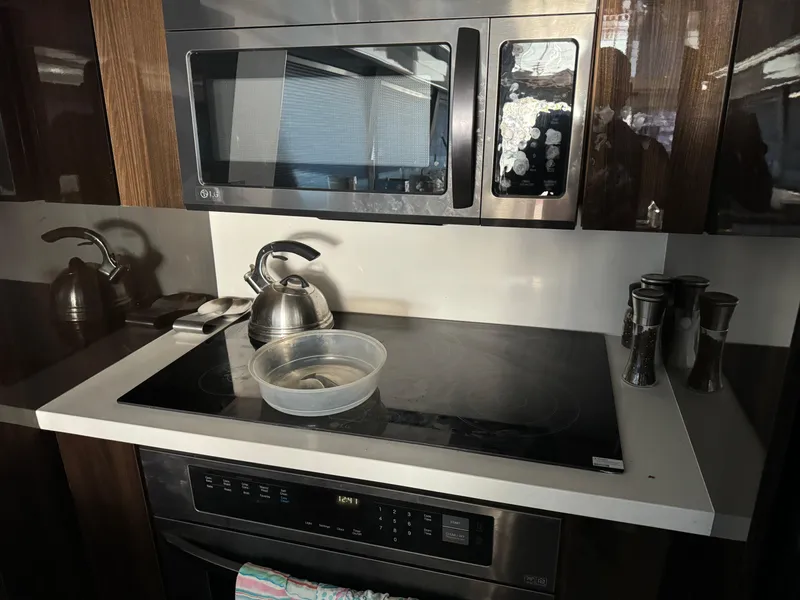 Modern kitchen in 1990 Versilcraft Challenger Motor Yacht with stove, microwave, and kettle.
