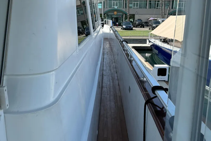 Side deck of 1990 Versilcraft Challenger Motor Yacht, featuring sleek white exterior and wooden walkway.