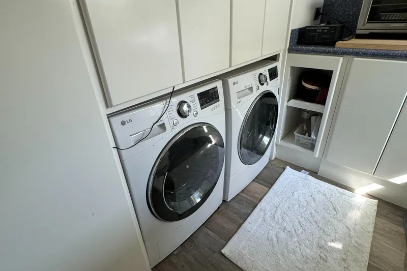 Laundry area with LG washer and dryer, white cabinets, and a rug on wooden floor.