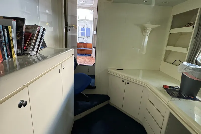 Interior of 1990 Versilcraft Challenger Motor Yacht with white cabinetry and blue carpet.