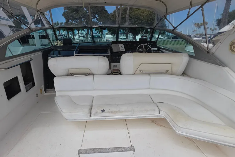 1988 Sea Ray 460 Express Cruiser cockpit with white seating and helm, docked at marina.