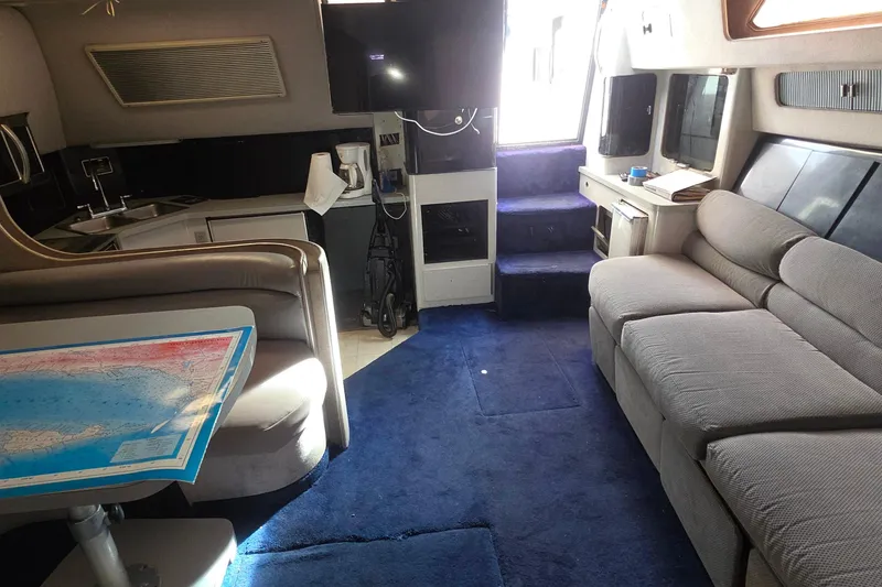 Interior of 1988 Sea Ray 460 Express Cruiser with blue carpet and comfortable seating.