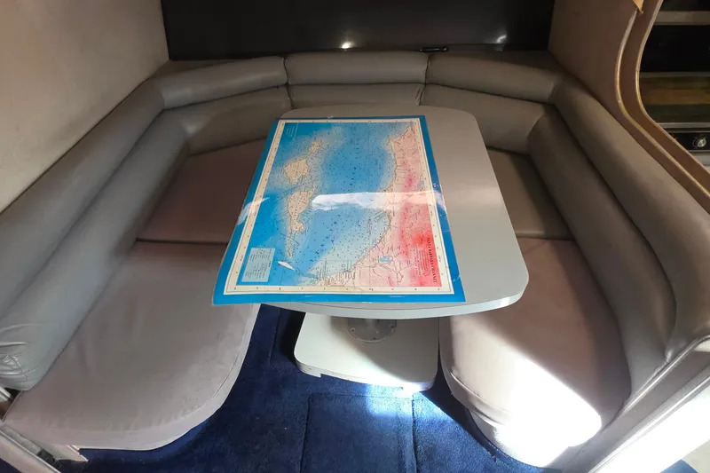 Interior of 1988 Sea Ray 460 Express Cruiser with map on table, surrounded by gray seating.