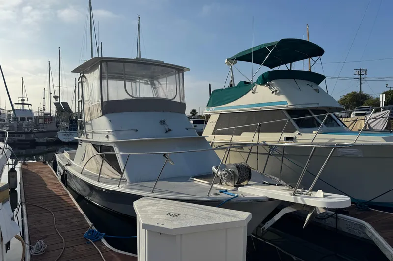 1984 Blackfin 32 Flybridge boat docked at marina, clear sky background.
