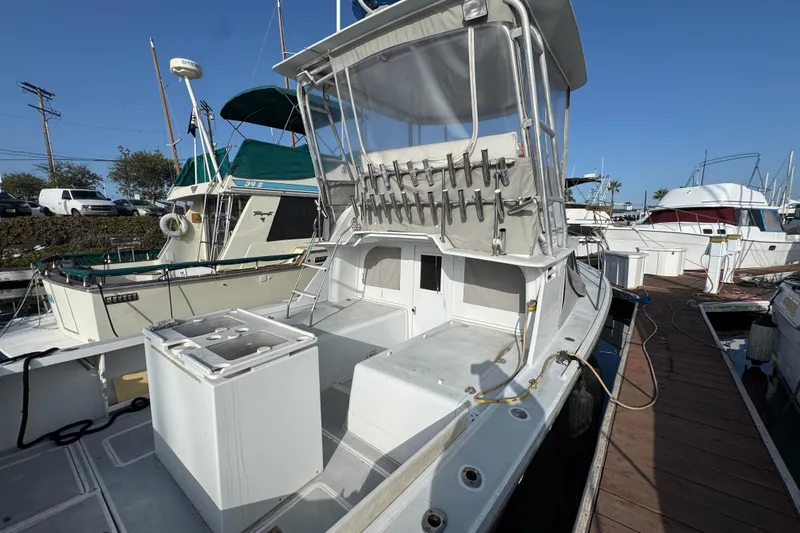 1984 Blackfin 32 Flybridge boat docked, featuring spacious deck and fishing rod holders.