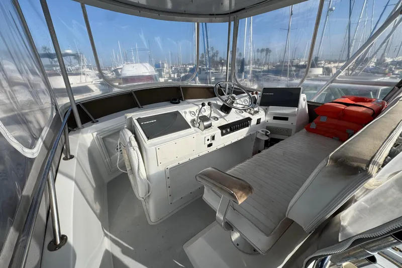 1984 Blackfin 32 Flybridge helm with steering wheel, navigation equipment, and life jackets.