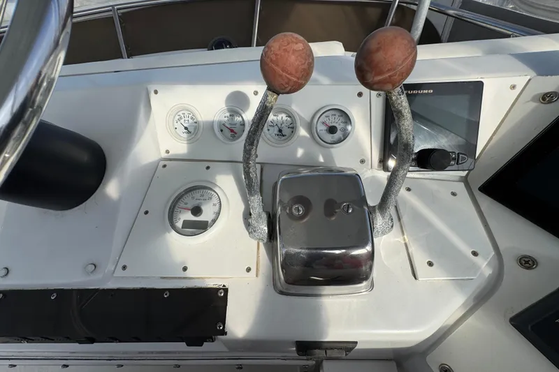 1984 Blackfin 32 Flybridge helm with gauges and controls, featuring dual throttle levers.