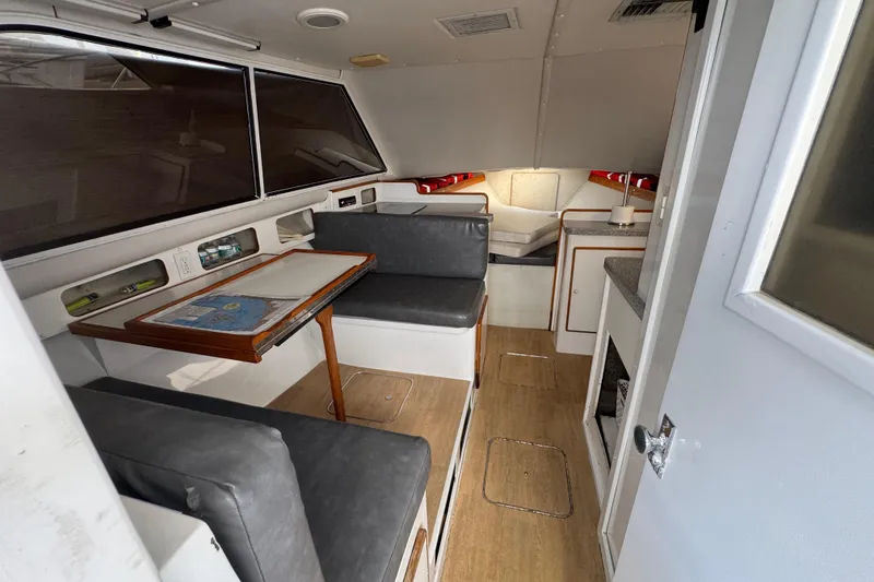 1984 Blackfin 32 Flybridge interior with seating, table, and compact kitchen area.