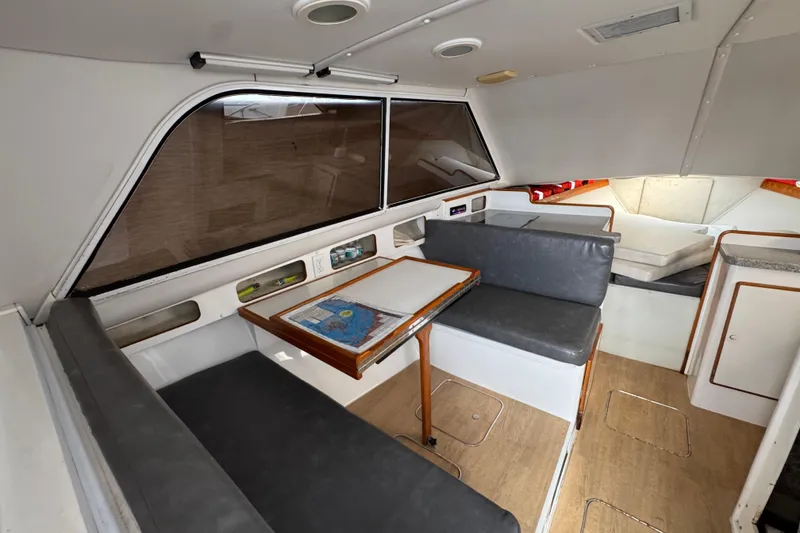 1984 Blackfin 32 Flybridge interior with seating, table, and cabin area.