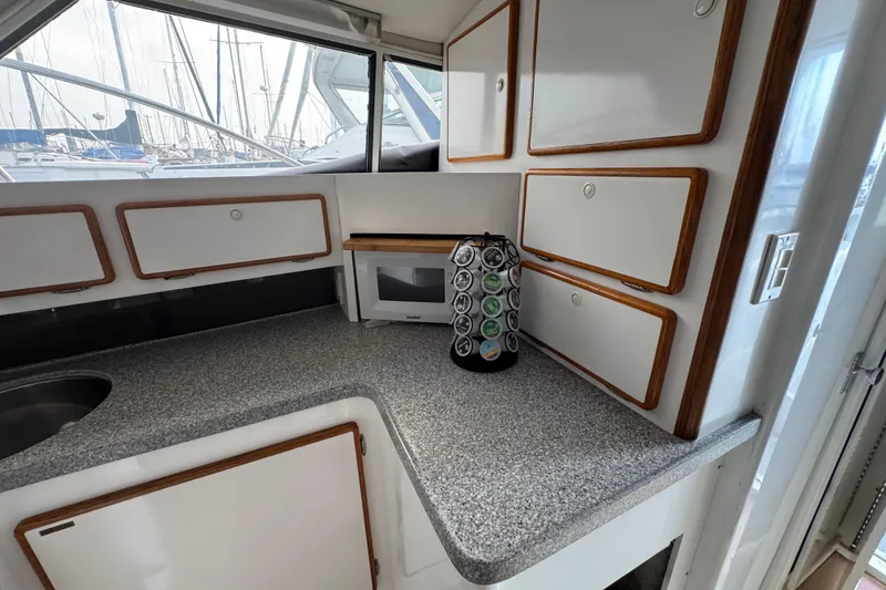 1984 Blackfin 32 Flybridge kitchen with cabinets, countertop, microwave, and spice rack.