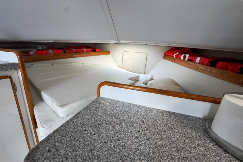1984 Blackfin 32 Flybridge cabin interior with bed, life jackets, and wooden trim.