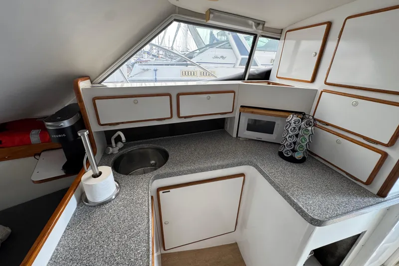 1984 Blackfin 32 Flybridge galley with sink, microwave, and storage cabinets.