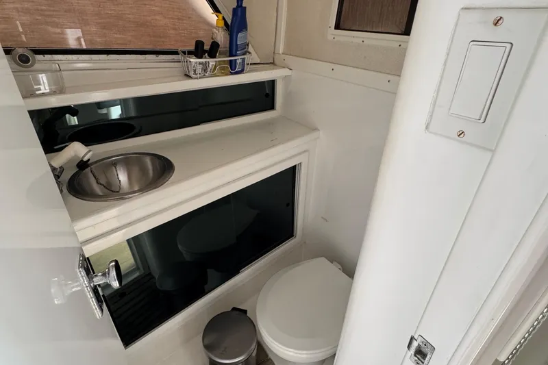 Compact bathroom in 1984 Blackfin 32 Flybridge, featuring sink, toilet, and storage.