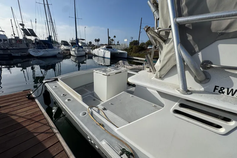 1984 Blackfin 32 Flybridge docked at marina, surrounded by sailboats under clear sky.