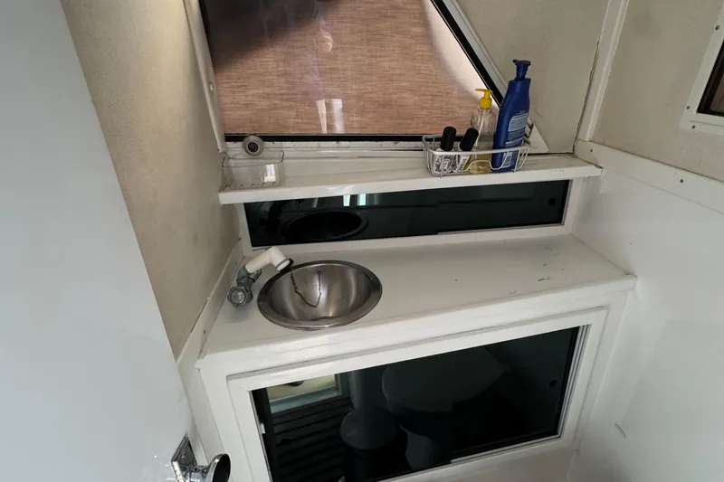 1984 Blackfin 32 Flybridge bathroom with sink, toiletries, and window.