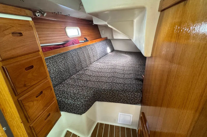 Cozy cabin interior of 1997 Catalina 36 MkII sailboat with wood paneling and patterned cushions.