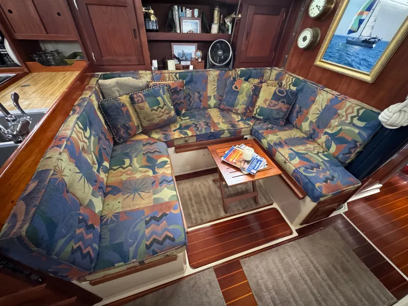 Interior of 1985 Catalina 36 MK1 sailboat with colorful cushioned seating and wooden accents.