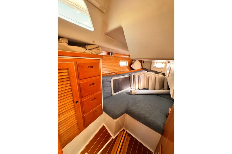 Cozy cabin interior of 1995 Catalina 36 MkII sailboat with wooden storage and bedding.