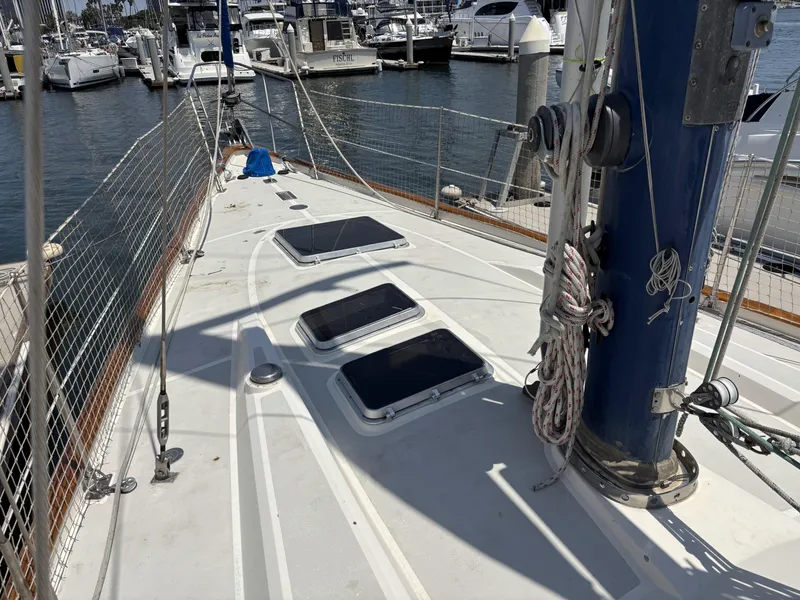 Deck of 1982 Norseman 447 sailboat in marina, featuring hatches and rigging.