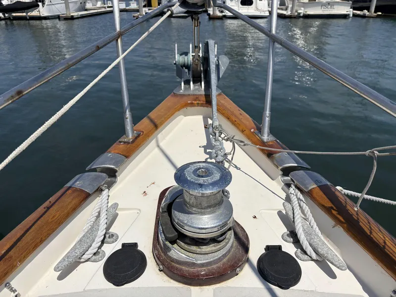 Bow of 1982 Norseman 447 sailboat with winch and ropes in marina.