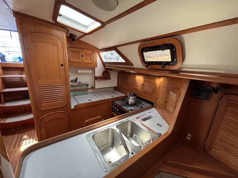 Interior of 1982 Norseman 447 sailboat kitchen with wooden cabinetry and stainless steel sink.