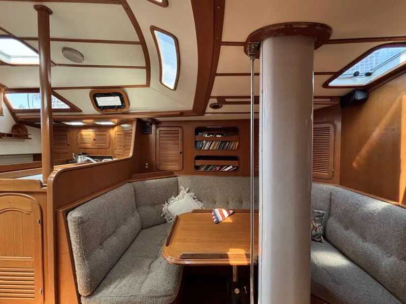 Cozy interior of 1982 Norseman 447 sailboat with wooden finishes and cushioned seating.