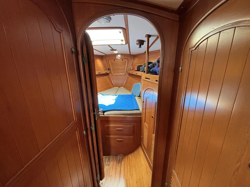 Cozy wooden cabin interior of 1982 Norseman 447 sailboat, featuring a bed and storage.