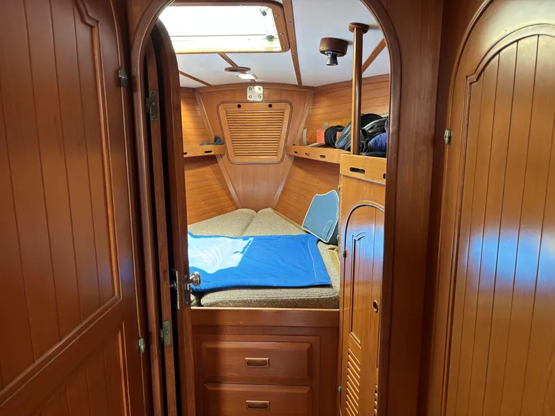 Cozy wooden cabin interior of 1982 Norseman 447 sailboat with bed and storage.