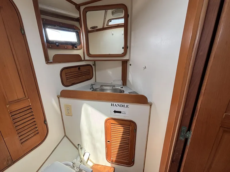 Compact bathroom in 1982 Norseman 447 boat with wooden accents and small sink.