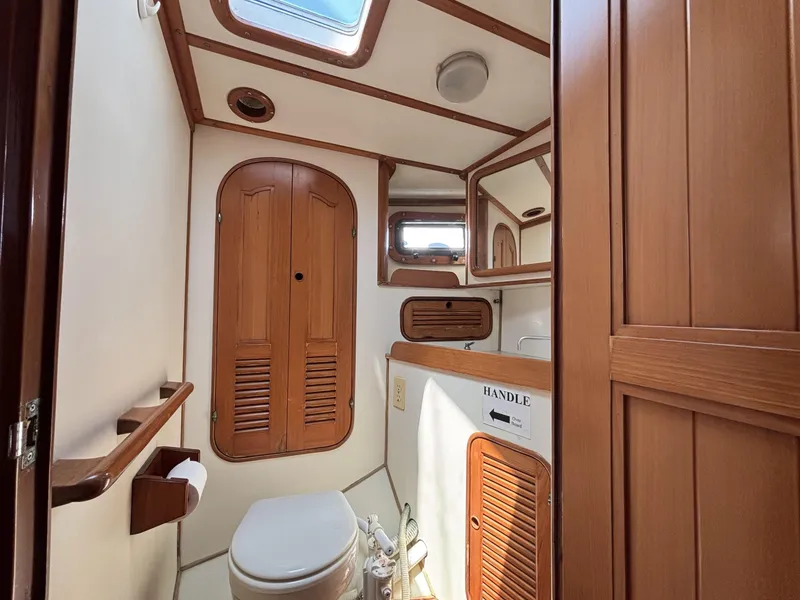 1982 Norseman 447 yacht bathroom with wooden cabinetry and skylight.