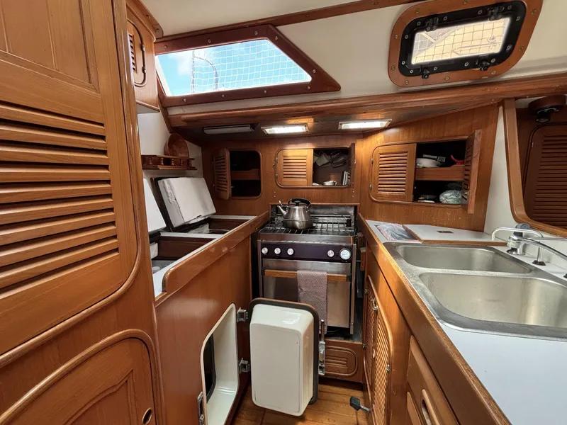 1982 Norseman 447 yacht kitchen with wooden cabinetry, stove, and sink.