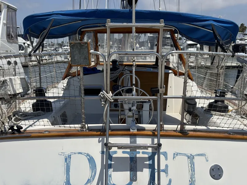 Sailboat Norseman 447, 1982 model, docked with blue canopy and visible steering wheel.
