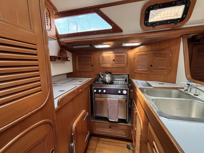 1982 Norseman 447 yacht kitchen with wooden cabinetry, stove, and sink.